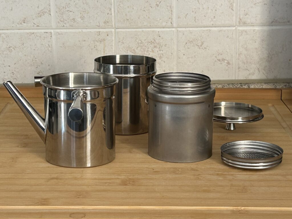 Cuccumella napoletana smontata con le sue parti: bricco inferiore, bricco superiore, filtro e coperchio.