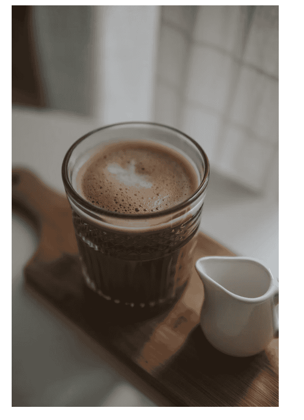 Bicchiere di caffè con crema su tagliere di legno in luce naturale