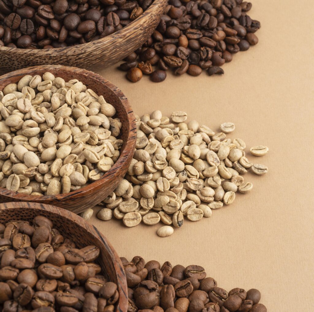 Chicchi di caffè verdi e tostati disposti in ciotole di legno.