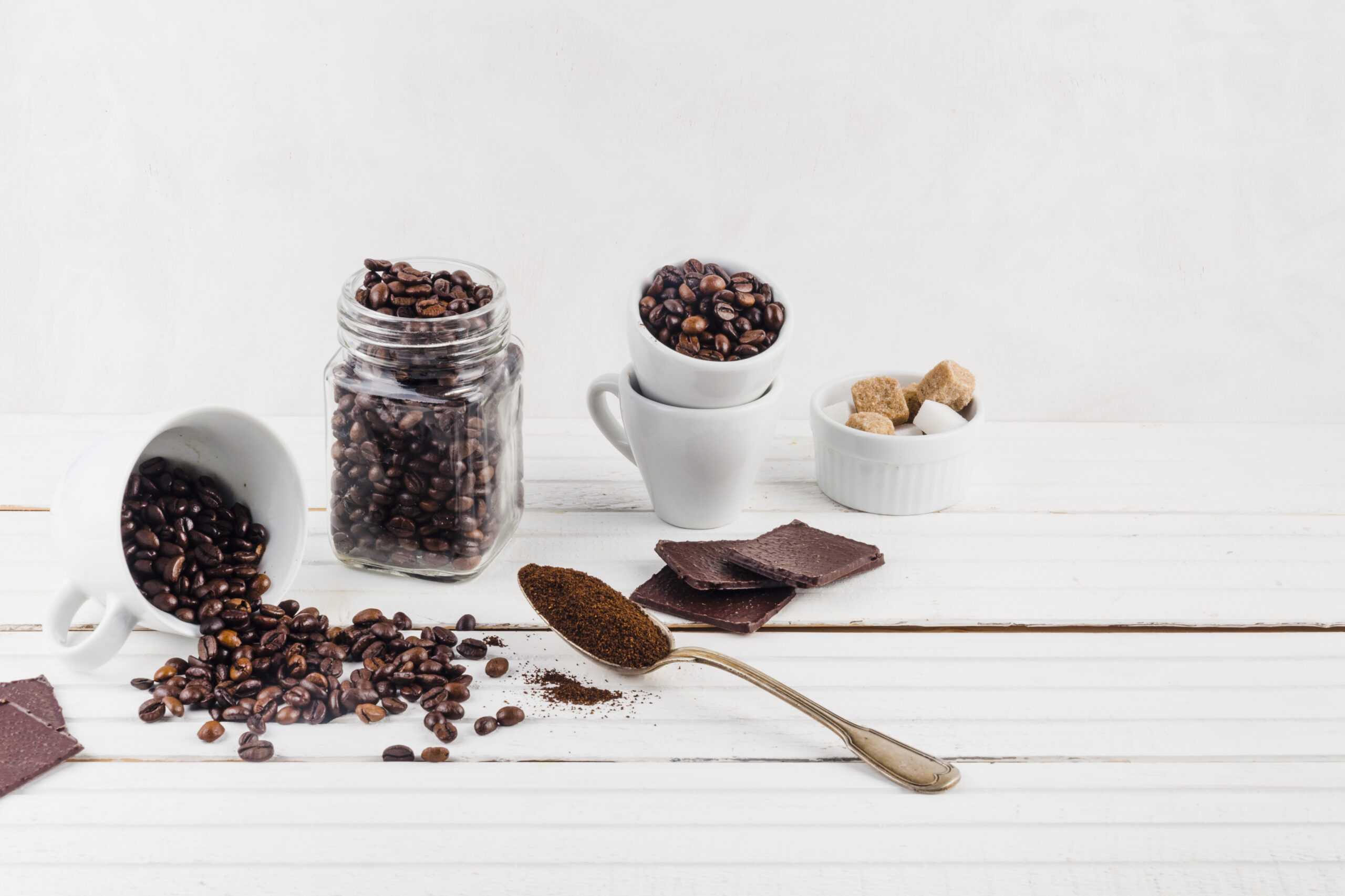 Chicchi di caffè e caffè macinato su sfondo chiaro, composizione minimal.