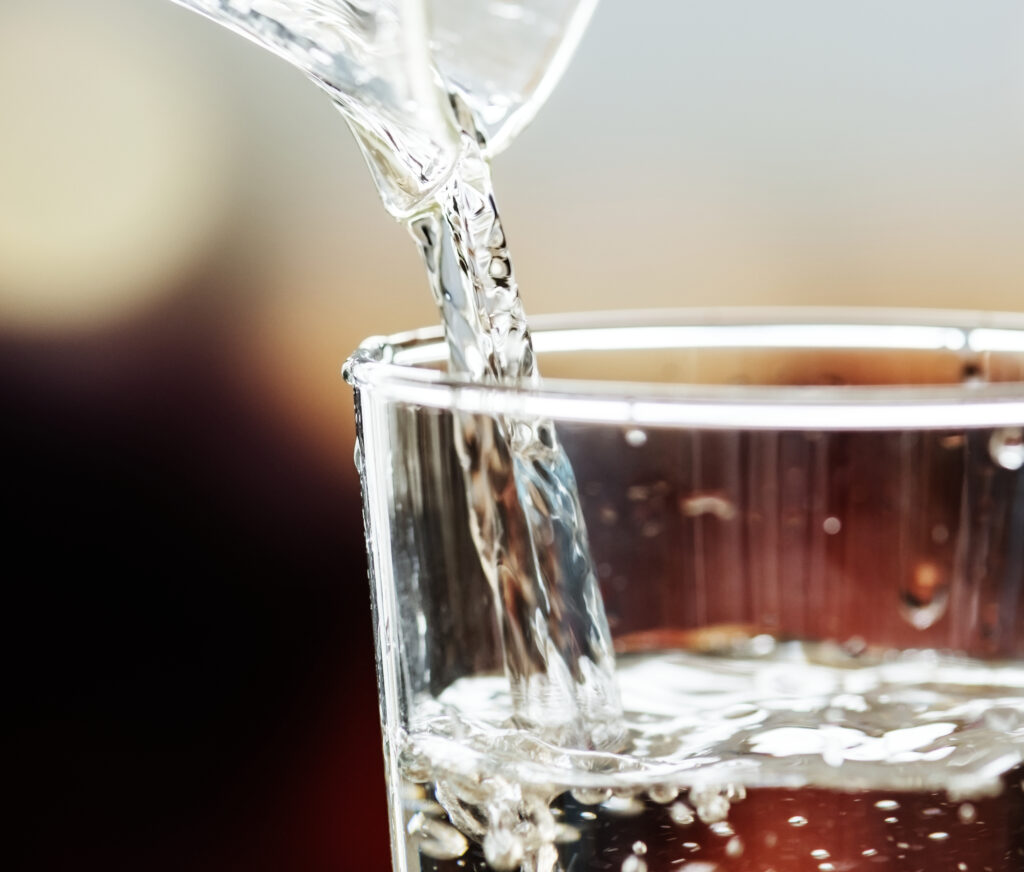 Acqua limpida versata in un bicchiere, simbolo dell’importanza della qualità dell’acqua per la moka