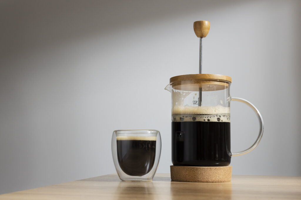 French Press in vetro con caffè appena estratto e tazza accanto