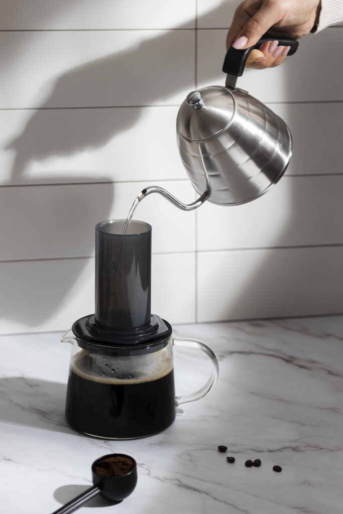 Acqua versata nell’Aeropress durante l’estrazione del caffè su caraffa in vetro
