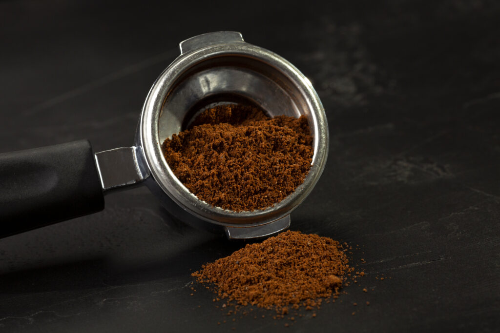 Portafiltro con caffè macinato, con parte della macinatura versata sul piano
