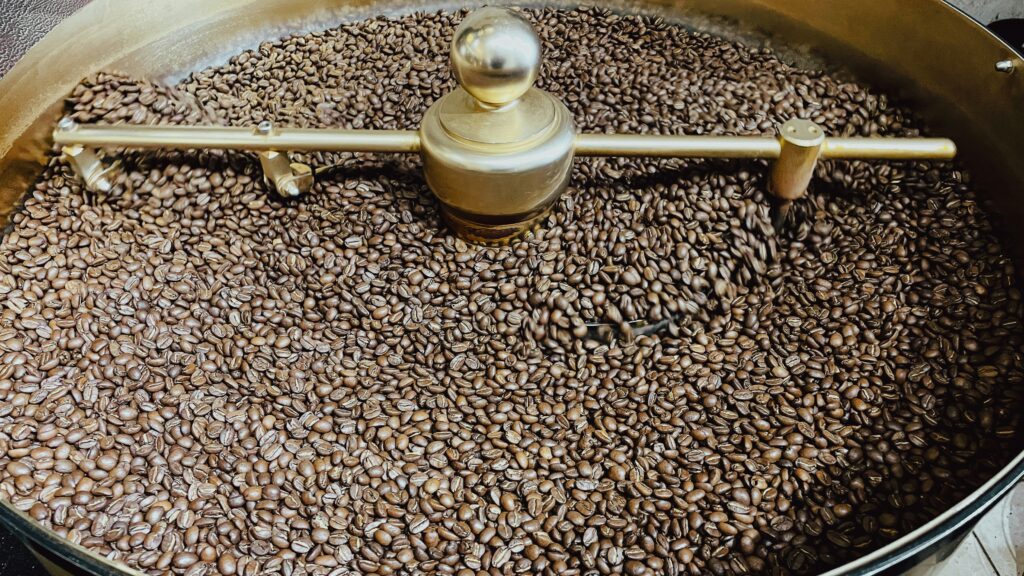 Tostatore a tamburo in funzione con chicchi di caffè a diversi livelli di tostatura